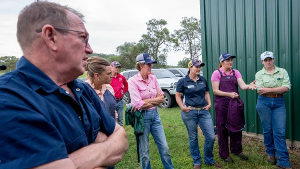ISJA banner group of poeple standing beside shed